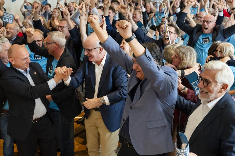 Participants celebrate the Ruhr Innovation Lab’s selection as a Consortium of Excellence with raised arms, blue flags and unicorn balloons.