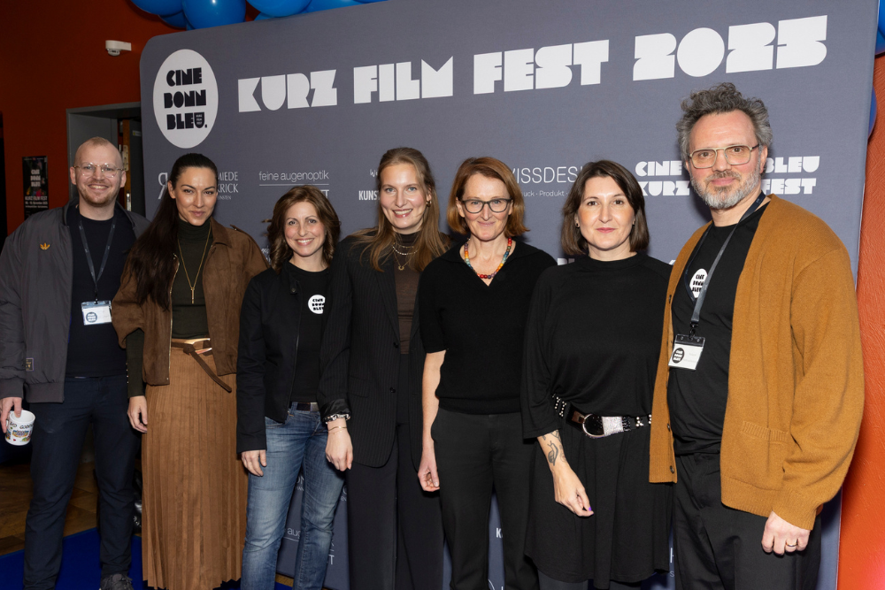 group of people standing in front of a photo wall