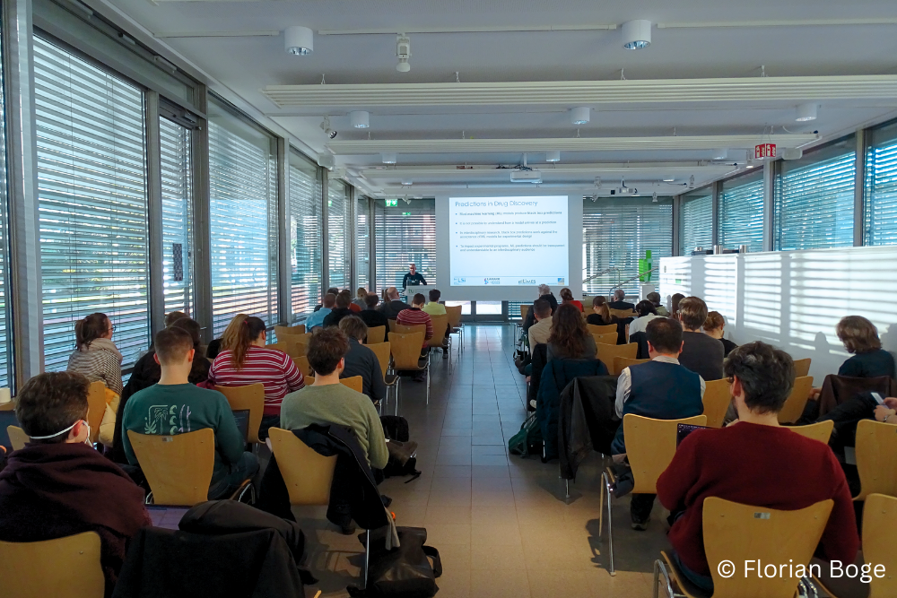 Photo. Conference rrom with people listening to talk by Jürgen Bajorath.